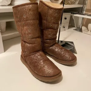 Uggs boots with light gold color logos all around the boots tan and gold
